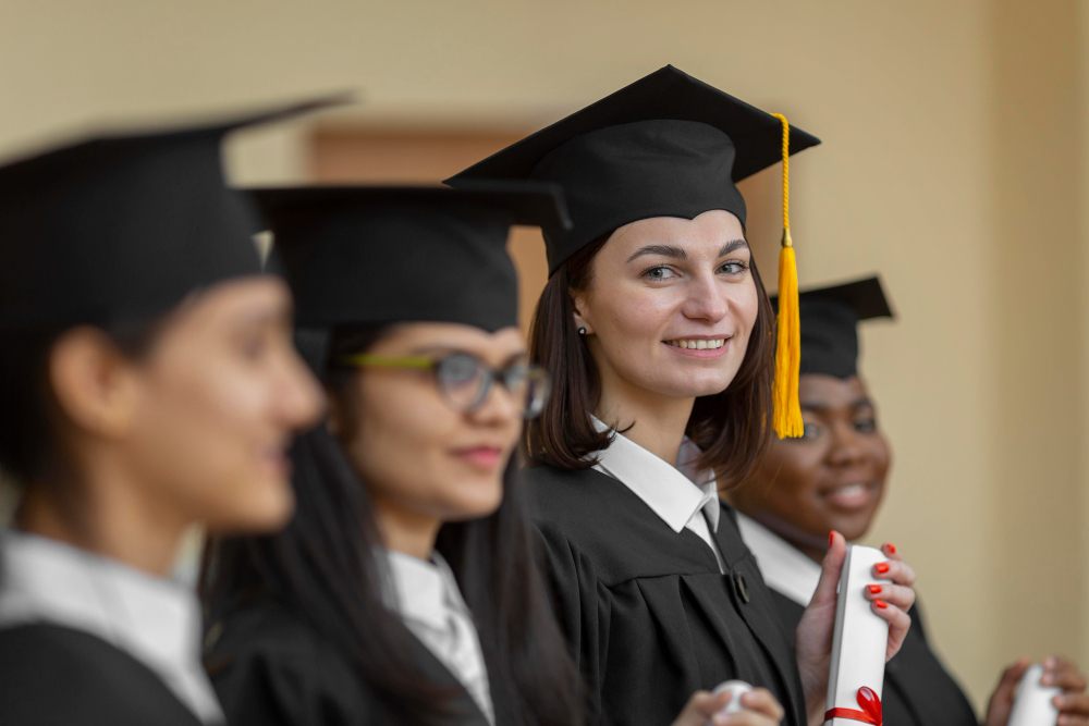 Smiling students in convocation gown and scroll